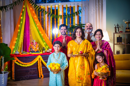 Indian Asian family performing Ganesh Puja at home in traditional attire, celebrating with devotion photo