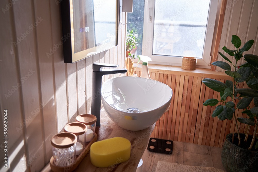 Fototapeta premium Bathroom with window and natural style plants with white sink and wood countertop with black faucet