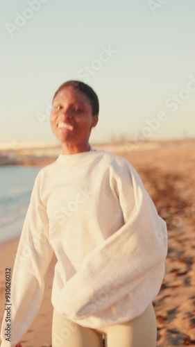 Veritical video of a happy girl in light colored clothes running on the beach  photo