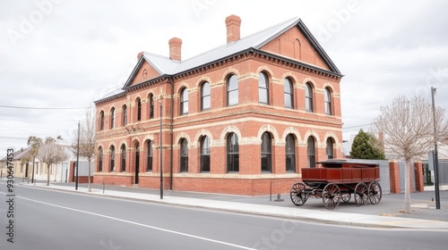 An antique black horse-drawn carriage rests beside an old South Australian prison building, featuring striking brown brick walls and a distinctive red tiled roof