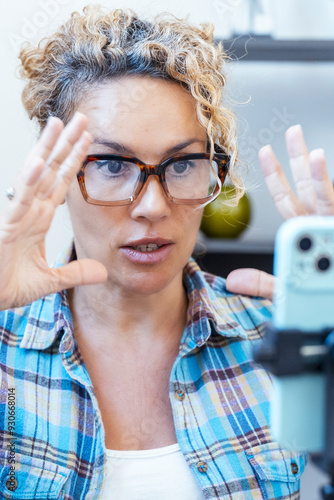 Female entrepreneur gesturing and speaking on a mobile phone while creating video content or conducting a videocall from home. A professional giving advice using voice and gestures in a digital worksp photo