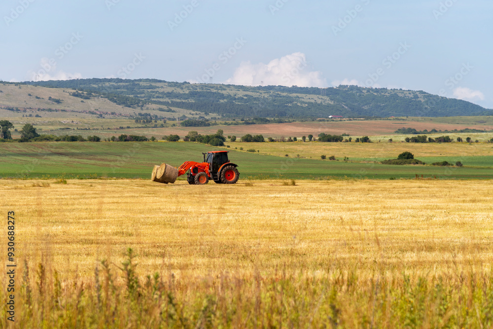 Tractor lifting hay bale on barrow. Tractor lifting hay bale on barrow.