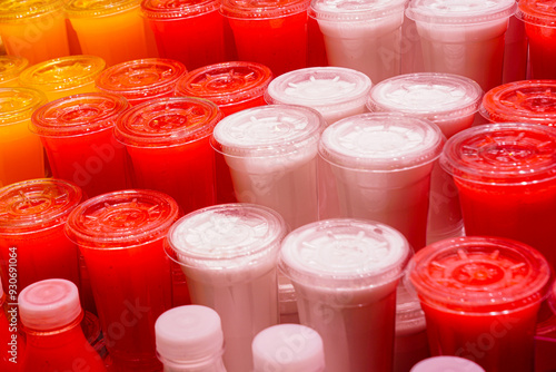 Canvas Print Freshly squeezed juices of various fruits in transparent plastic cups at a marke