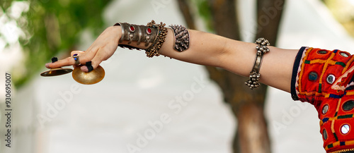 A dancer showcases traditional Indian movements adorned in vibrant attire during a cultural festival in a lush garden setting. One hand in a dance move photo