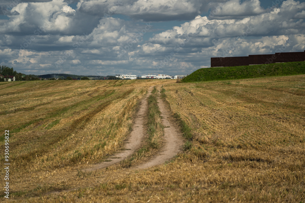 Thick clouds over a dirt road in a field. The road to the field after harvest Thick clouds over a dirt road in a field. The road to the field after harvest