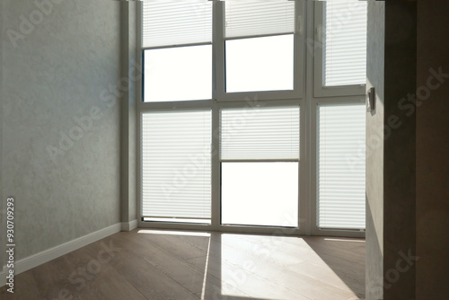 Billede på lærred Fragment of the apartment interior with a large glass window with white pleated curtains drawn