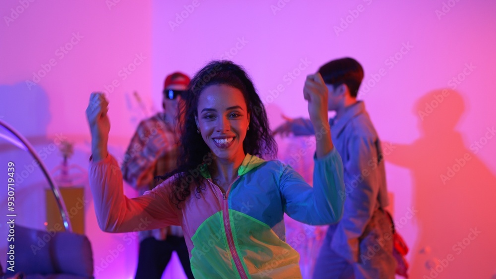 Attractive happy dancer looking at camera while smart woman moving at rhyme with neon light. Professional hispanic performer break dancing while wearing colorful cloth with diverse friend. Regalement. Attractive happy dancer looking at camera while smart woman moving at rhyme with neon light. Professional hispanic performer break dancing while wearing colorful cloth with diverse friend. Regalement.