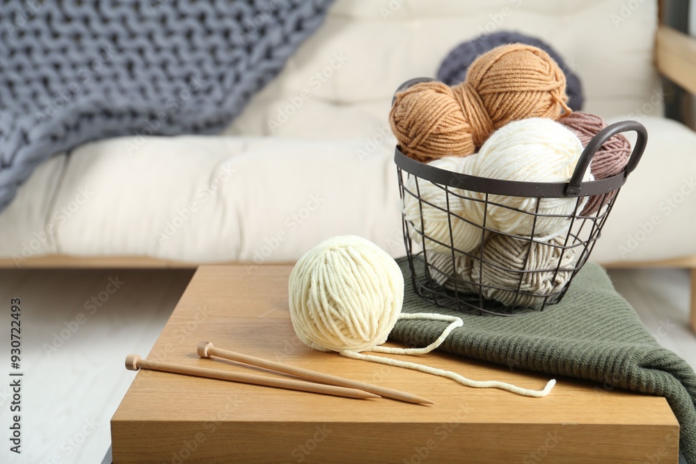 Basket with yarns, knitting needles and sweater on coffee table indoors Basket with yarns, knitting needles and sweater on coffee table indoors