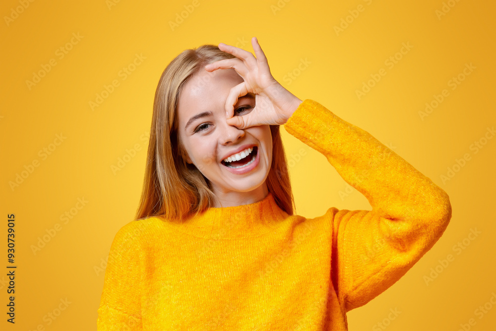 Everything is ok. Cheerful teen girl showing ok sign, gesturing with fingers near her eye, orange background Everything is ok. Cheerful teen girl showing ok sign, gesturing with fingers near her eye, orange background