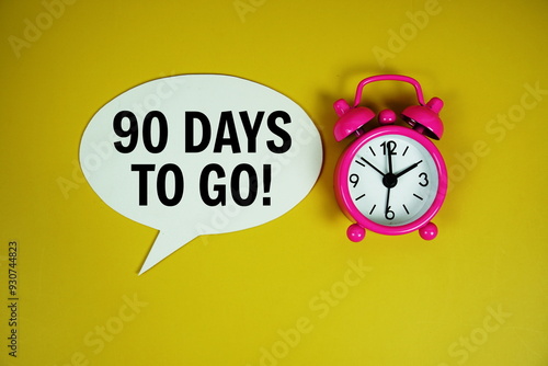 90 Days to go text on speech bluble with alarm clock top view on yellow background photo