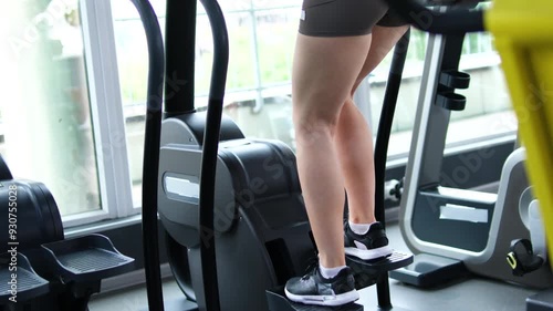 girl trains her legs and glutes on a stepper at modern gym, low angle shot