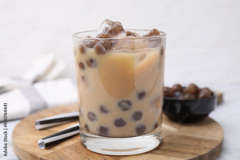 Tasty milk bubble tea in glass, tapioca pearls and straws on table, closeup Tasty milk bubble tea in glass, tapioca pearls and straws on table, closeup