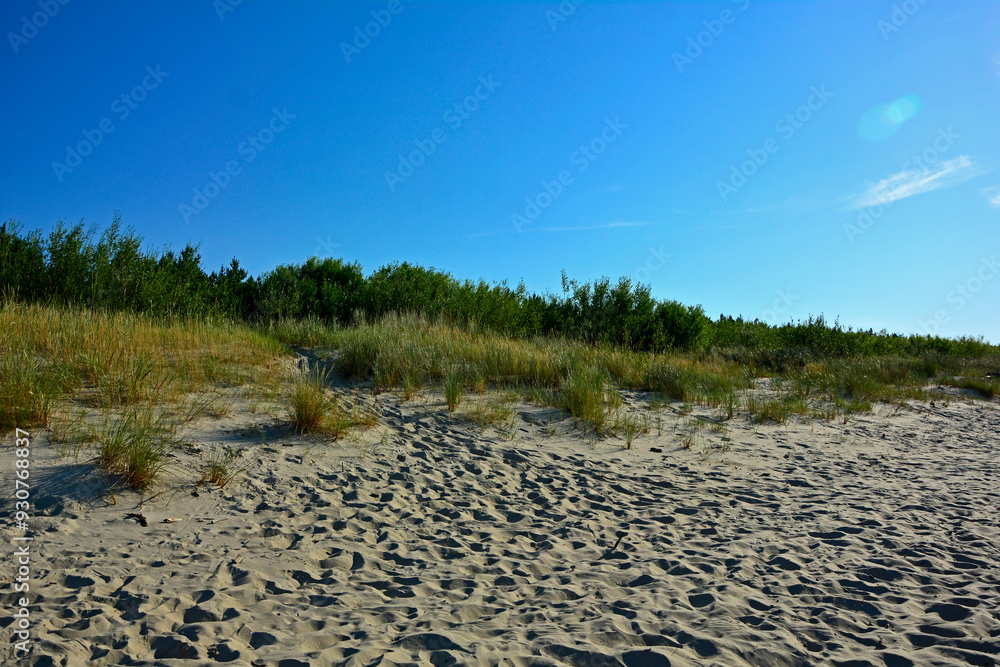 piaszczysta wydma nadmorska, piaszczysta wydma z trawami na tle niebieskiego nieba, seaside sand dune, sand dune with grasses against the background of the sky, nadmorski pejzaż