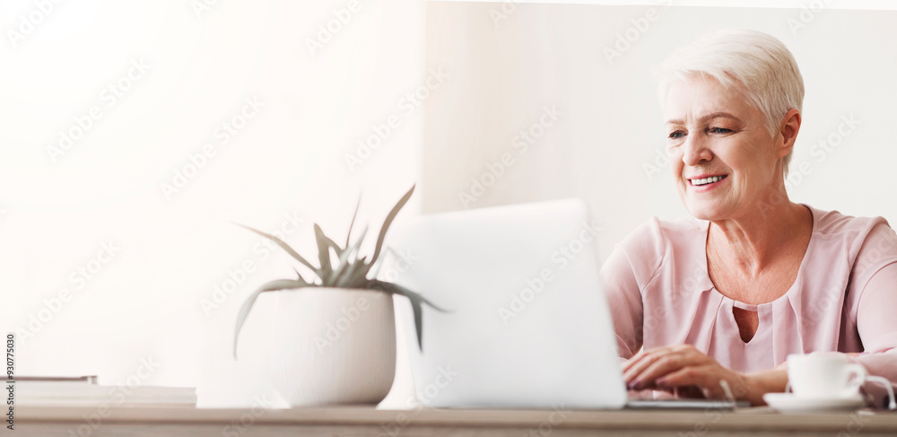Senior cheerful woman working with laptop, drinking coffee, free space Senior cheerful woman working with laptop, drinking coffee, free space