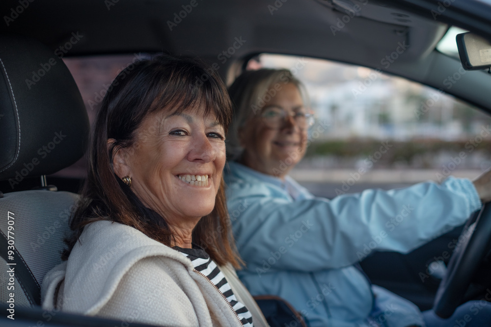 Two smiling senior women sitting inside the car ready for travel adventure freedom Two smiling senior women sitting inside the car ready for travel adventure freedom