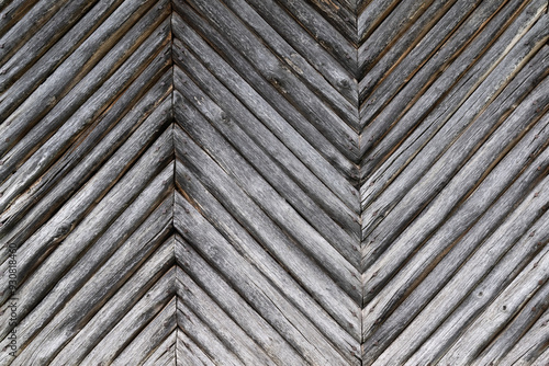 Holzwand im Fischgrätmuster, Stangenholz, Rundholz, Außenwand, genagelt,grau