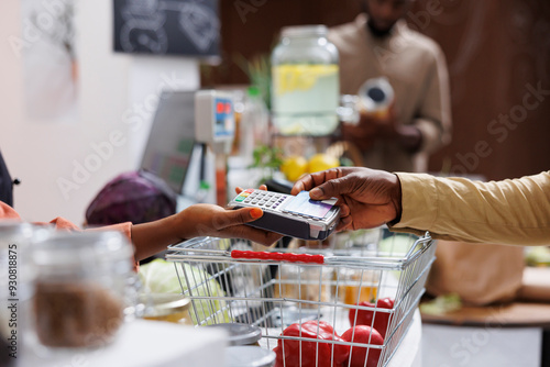 Photography Close-up shot of hand tapping a debit card on the terminal, symbolizing a secure and efficient transaction