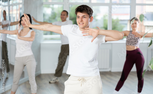 Happy young man and group of international dancers training before big performance in modern dance class