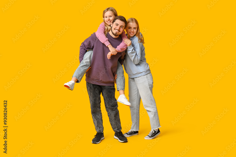 Happy family in stylish denim clothes having fun together on yellow background Happy family in stylish denim clothes having fun together on yellow background