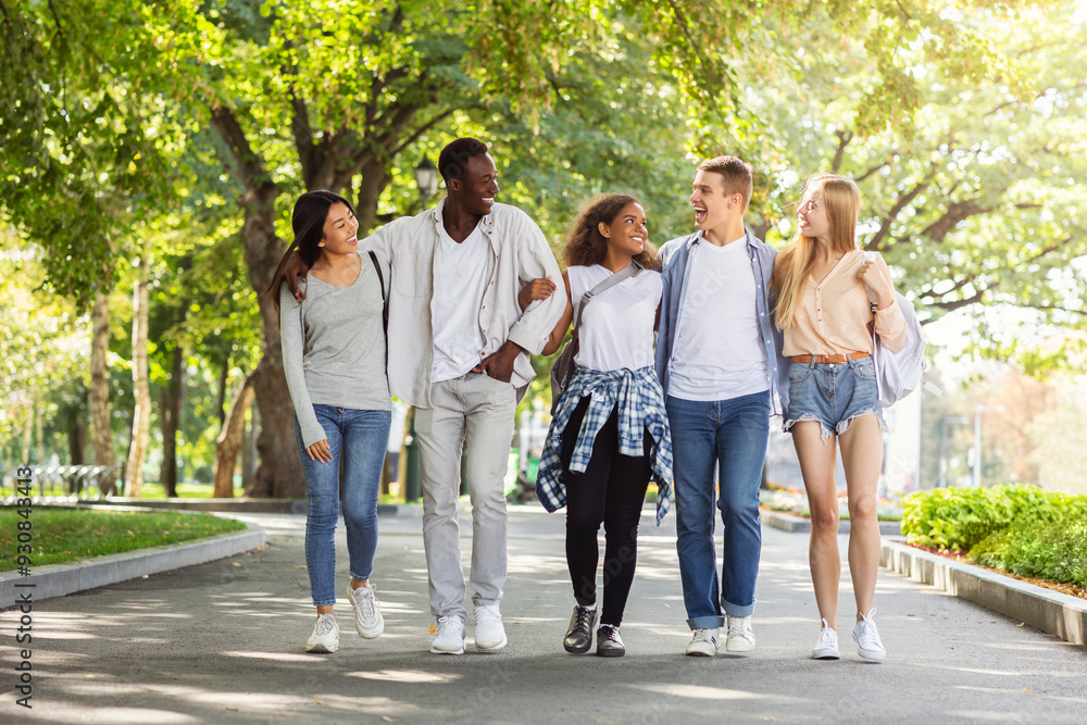 Multiethnic group of students walking in park after university, happily chatting and having fun, copy space Multiethnic group of students walking in park after university, happily chatting and having fun, copy space