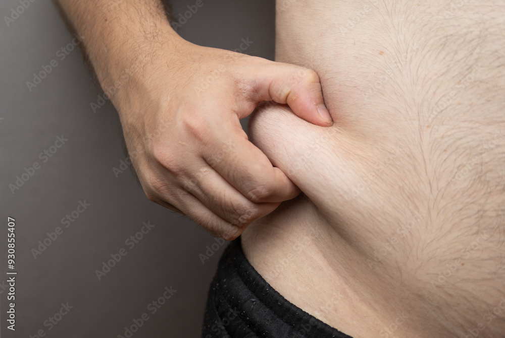A close-up image of a person pinching their belly, symbolizing concern about body fat and the desire to lose weight. A close-up image of a person pinching their belly, symbolizing concern about body fat and the desire to lose weight.