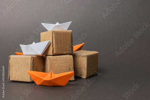 Cardboard boxes stacked with paper boats on top, representing the careful coordination required between packaging and transportation in the export industry.
