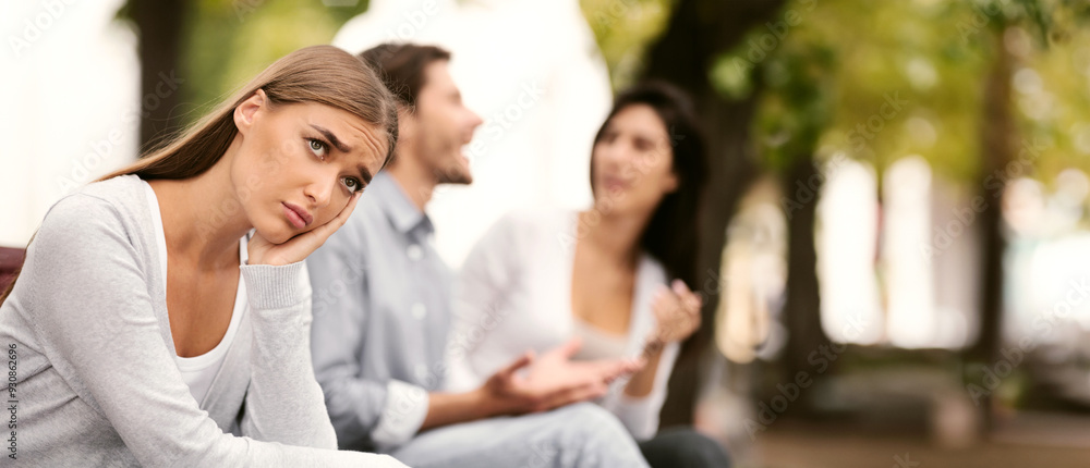 Fototapeta premium Lonely Girl Suffering From Loneliness Sitting Next To Happy Lovers On Bench In Park Outdoor. Selective Focus