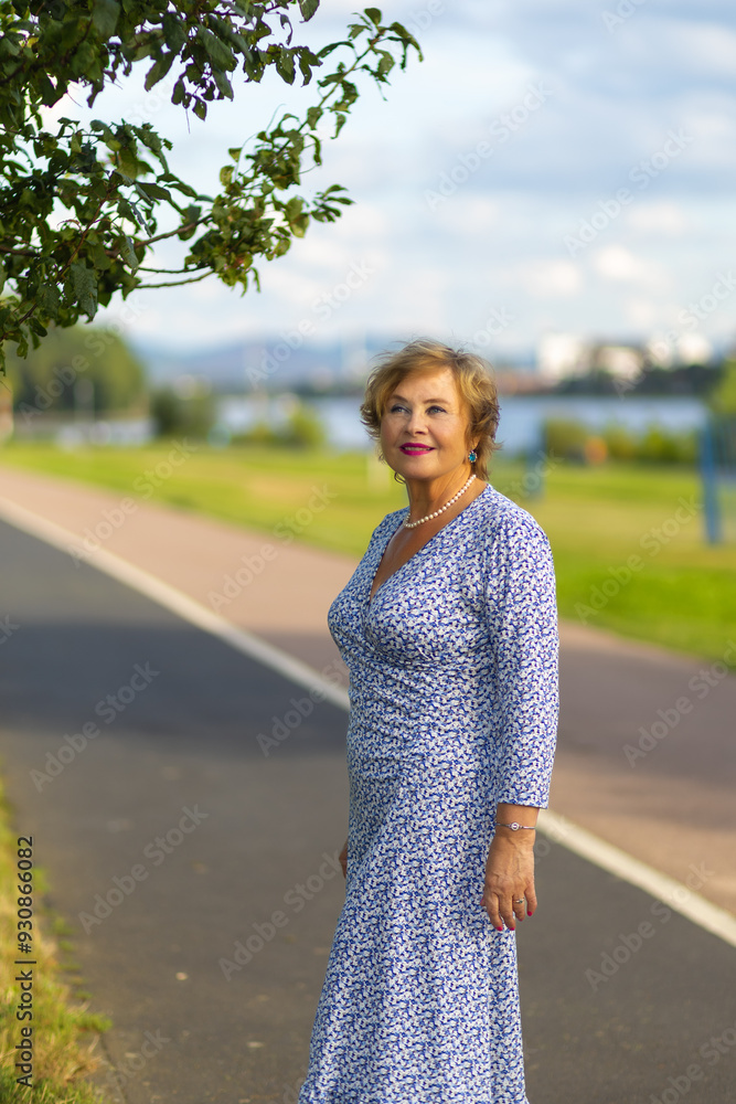 Fototapeta premium Woman in blue floral dress enjoying a sunny day by the riverbank