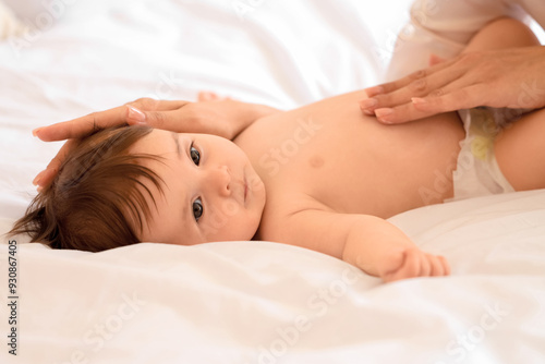 Mother applying cream on little baby's belly in bedroom, closeup