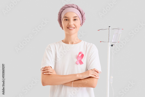 Young woman with pink ribbon undergoing chemical therapy course on light back...