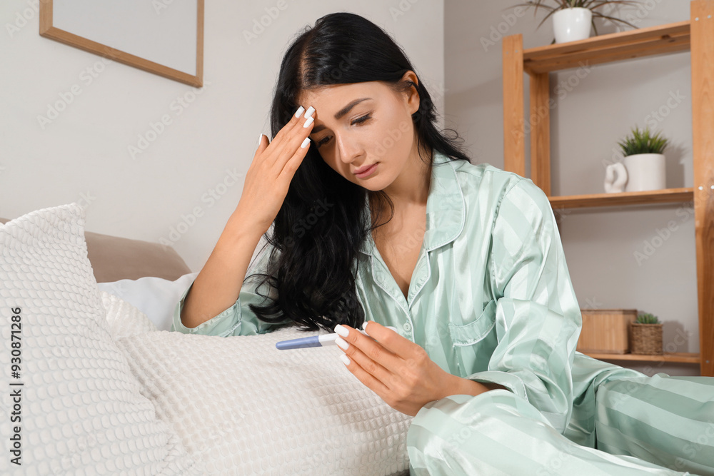 Upset young woman with pregnancy test in bedroom Upset young woman with pregnancy test in bedroom
