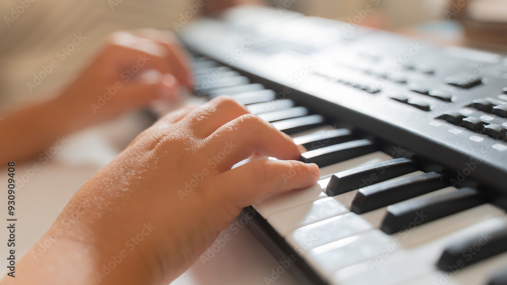 Fototapeta premium close-up of a child's hands playing the keys of a piano synthesizer