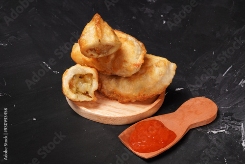 Fried stuffed Cireng, a traditional Indonesian snack filled with seasoned beef fat or jando, perfect with chili sauce dip, photographed against a dark background. photo