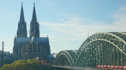 A bridge spans a river with a cathedral in the background. The bridge is a metal structure with a green color