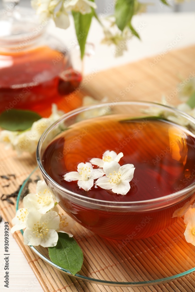 Hot jasmine tea in cup and flowers on white table, closeup Hot jasmine tea in cup and flowers on white table, closeup