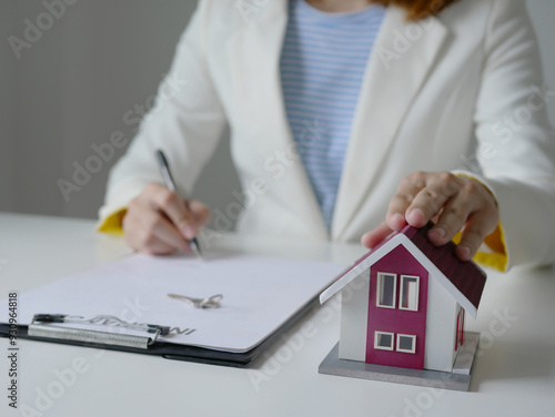 Pretty real estate agent signs documents and hands over house keys to client House selling concept and home insurance