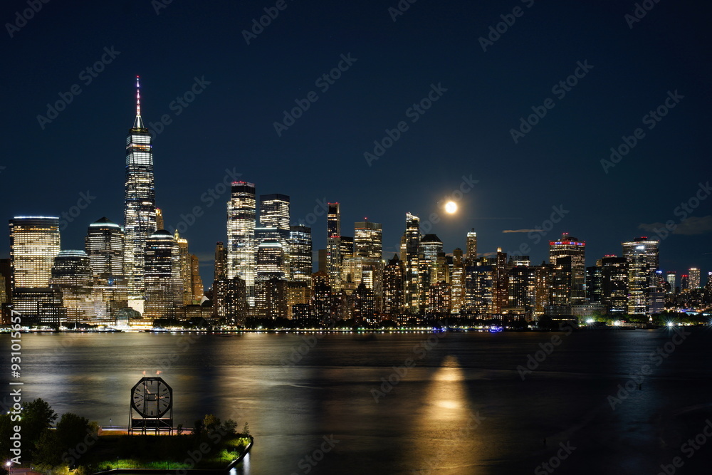 Obraz premium The lights of Manhattan skyscrapers on a moonlit night.