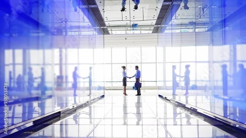 Two business people shaking hand in the hallway of modern office building, slow motion video