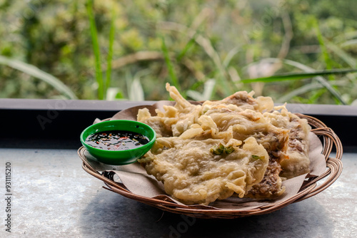 Tempe mendoan is served with sweet and spicy soy sauce, an Indonesian food or snack made from thinly sliced ​​tempeh, coated in flour, then fried in hot oil. photo