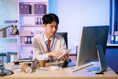 Overtime work concept, Handsome asian business man working overtime sitting at desk using computer and doing overtime project