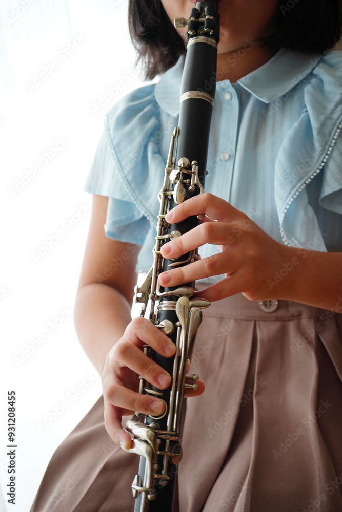 Fototapeta premium 吹奏楽部でクラリネットパートを担当している小学5年生の女の子。自宅で自主練。