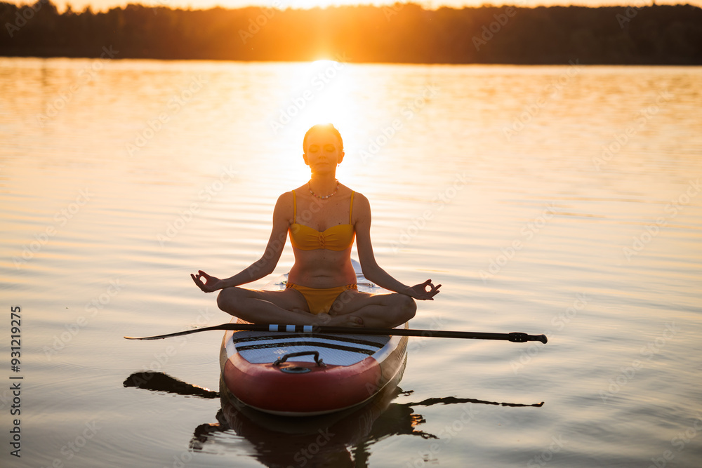 Young woman on Sup board doing yoga on sunrise or sunset background, Sup surfing concept Young woman on Sup board doing yoga on sunrise or sunset background, Sup surfing concept
