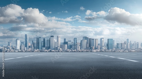 Fototapeta Naklejka Na Ścianę i Meble -  Empty asphalt road in front of a modern city skyline with a cloudy blue sky.