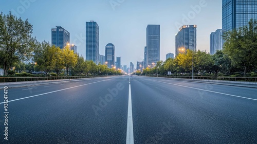 Empty asphalt road in the city with skyscrapers and trees on both sides.