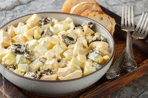 Chicken cream salad with prunes, cucumber and eggs close-up in a bowl on the table. Horizontal