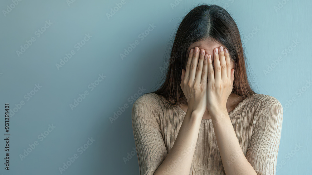 A young woman expresses sadness while covering her face with her hands, conveying sense of distress and vulnerability. A young woman expresses sadness while covering her face with her hands, conveying sense of distress and vulnerability.