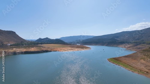 Aerial cruises above the sparkling waters of Lake Iznajar towards lakeside beach and pleasure boats, and exposing the steady decrease of water levels due to global warming and over use of water Spain
