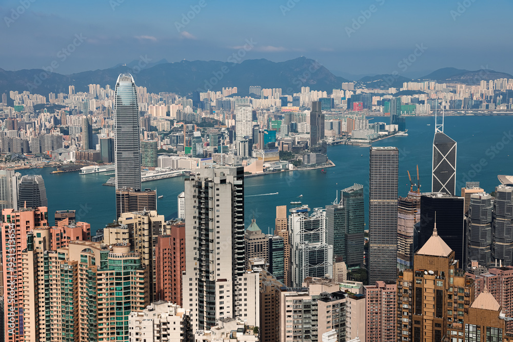 Victoria Bay in Hong Kong showcasing skyscrapers and vibrant waterfront under a clear blue sky Victoria Bay in Hong Kong showcasing skyscrapers and vibrant waterfront under a clear blue sky