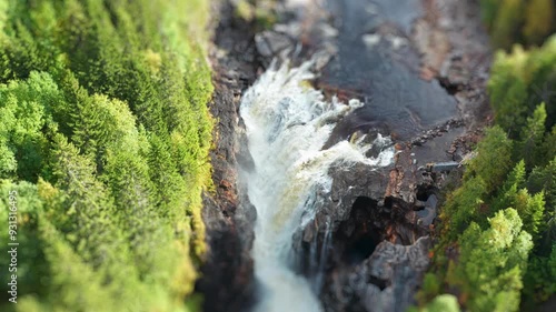 A tilt-shift video of the Formofoss waterfall cascading down the canyon. Trees on both sides of the gorge. Aerial view. High-quality 4k footage photo