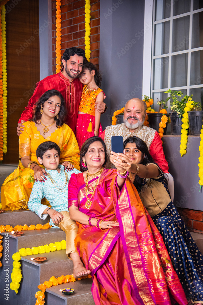 Naklejka premium Indian family in traditional attire taking a group selfie on steps in Diwali or festival celebration